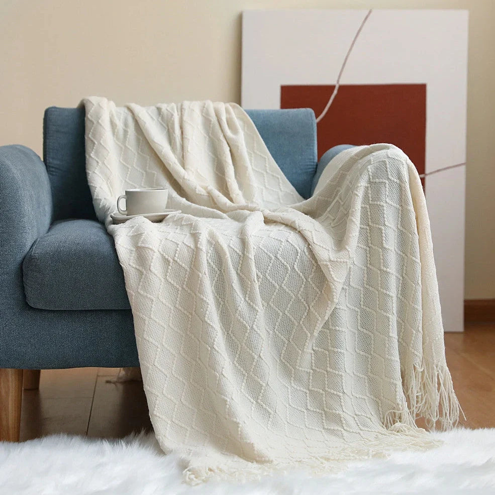 Nordic knitted blanket in beige colour showing open knit pattern on grey sofa