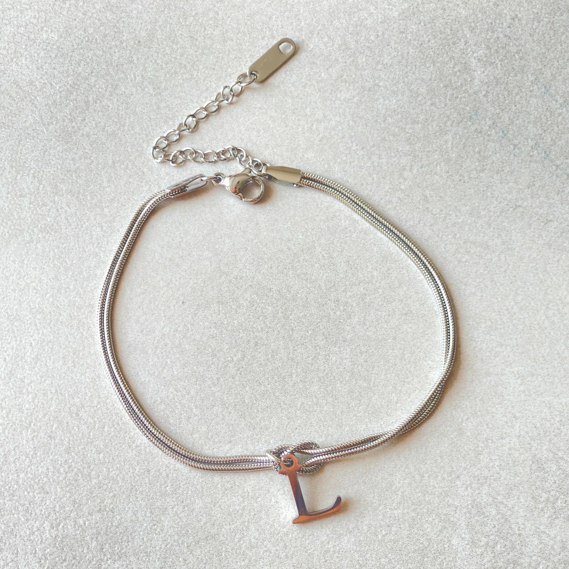 Elegant letter charm bracelets for women in gold and silver tones, featuring a delicate snake chain design and personalised letter charms.