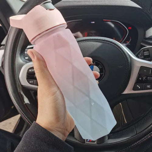 White spray water bottle with black leakproof lid and handle strap on a table
