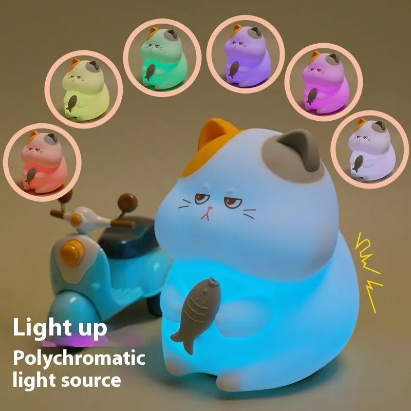 Yellow cartoon Greedy Cat desktop night light with plug, shown on a wooden desk.