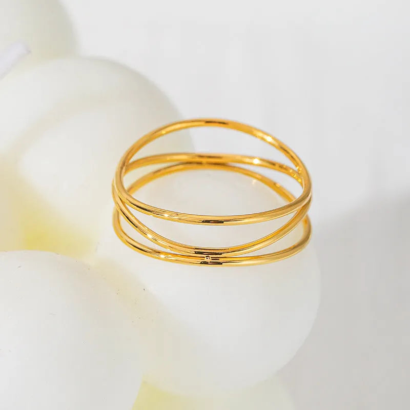Gold titanium steel geometric coil ring with three-layer design on a model's finger.