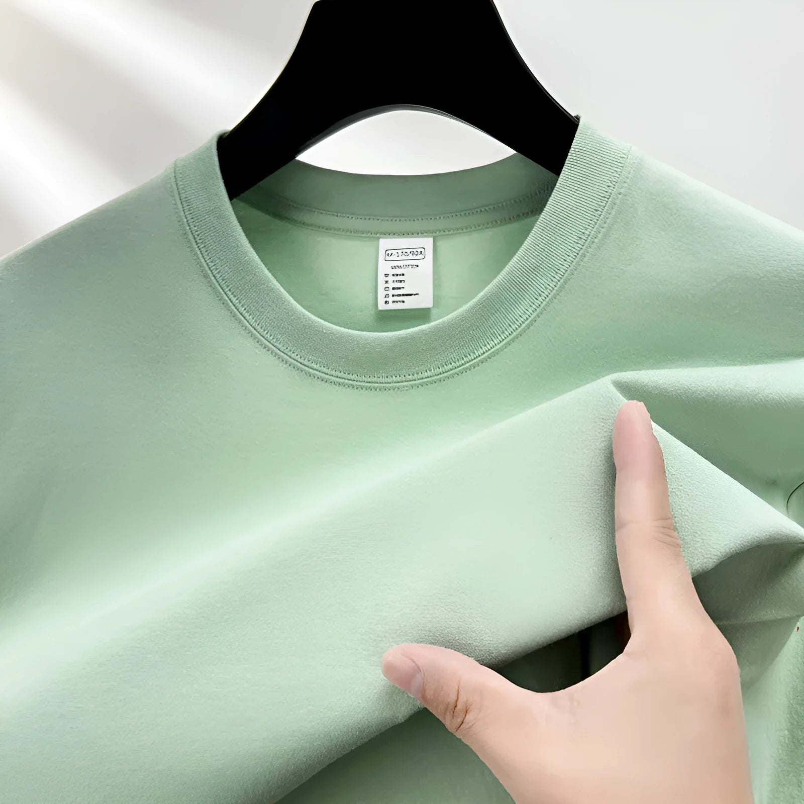 Men's thin cotton drop shoulder t-shirt on a hanger, shown in a light colour.