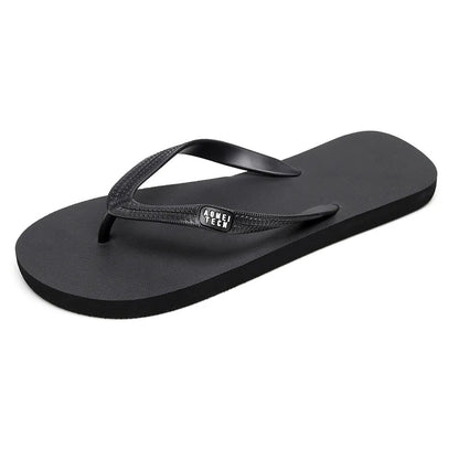 Men's black flip-flop slippers with EVA upper and textured rubber sole on a sandy background.