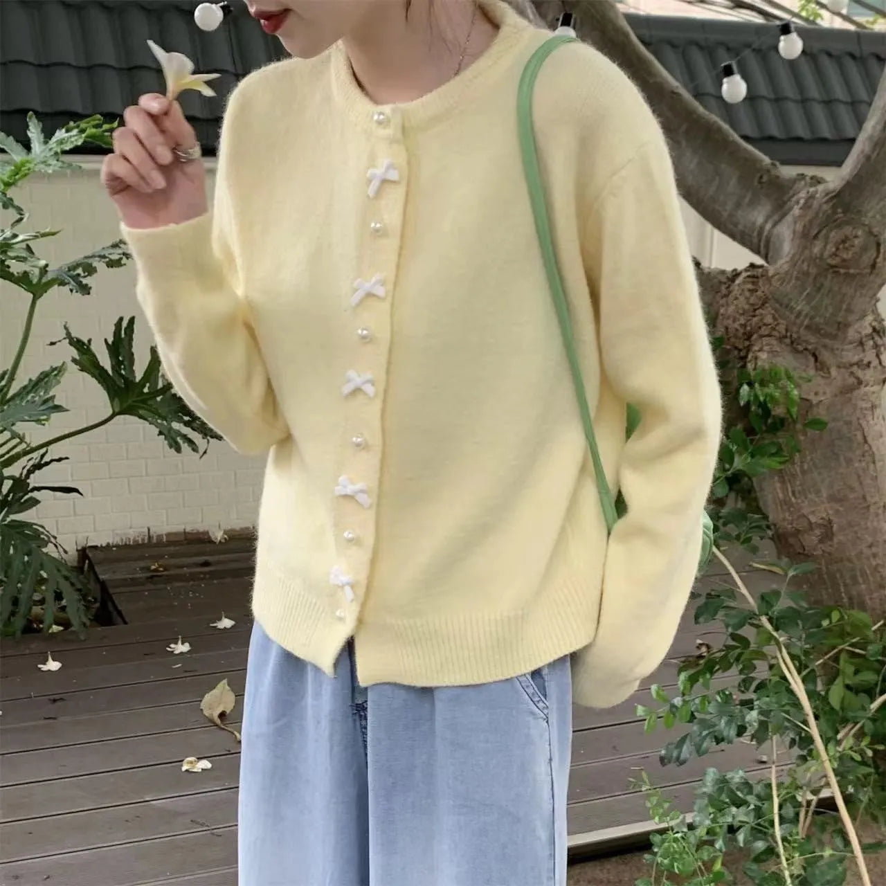 Women's acrylic cardigan sweater with pearl button bow detail in light yellow colour