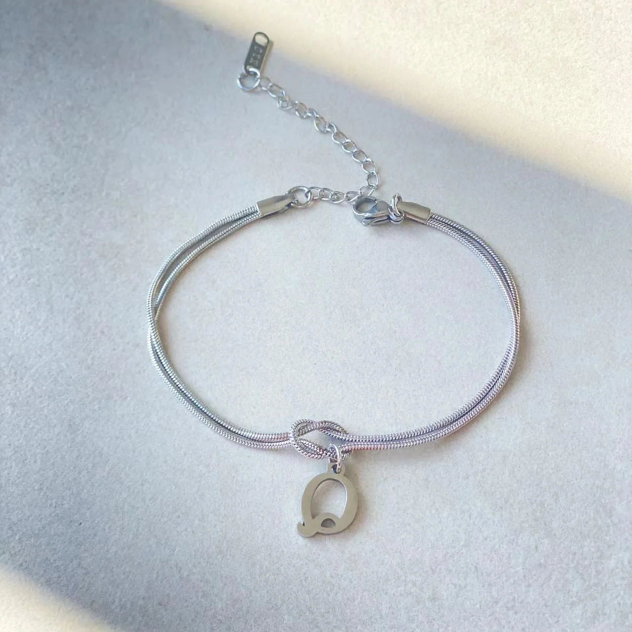 Elegant letter charm bracelets for women in gold and silver tones, featuring a delicate snake chain design and personalised letter charms.