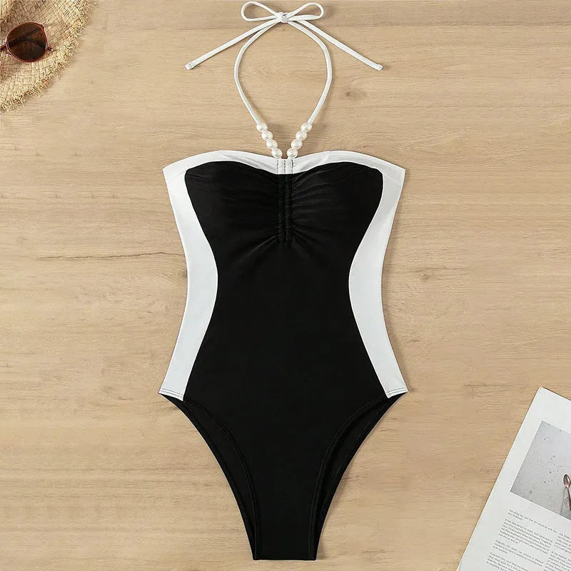 Women's black and white one-piece swimsuit with pearl spaghetti straps and a slimming silhouette.