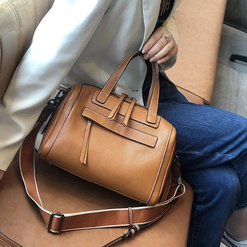 Genuine leather horizontal messenger bag in wine red with shoulder strap and internal zippered compartments.