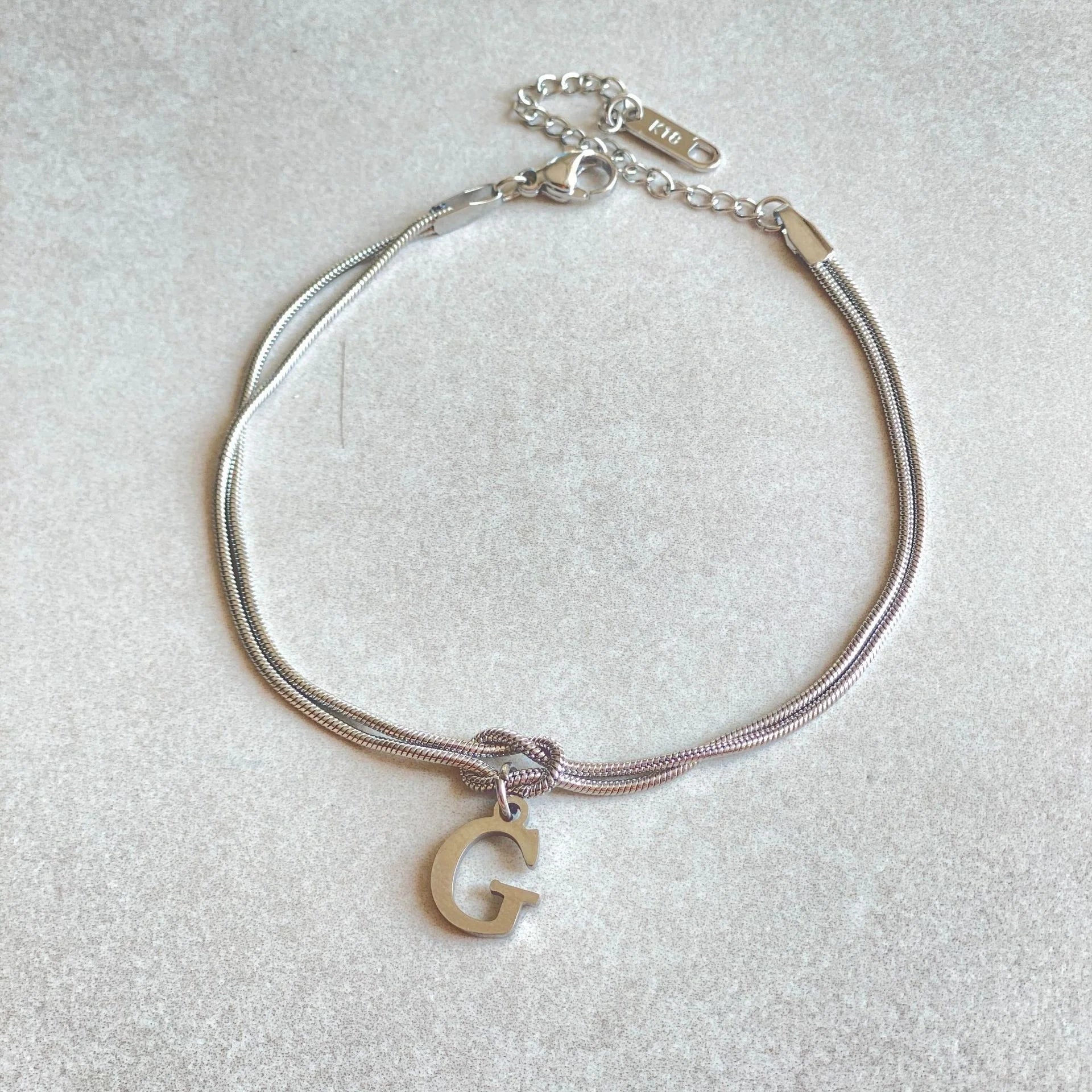 Elegant letter charm bracelets for women in gold and silver tones, featuring a delicate snake chain design and personalised letter charms.