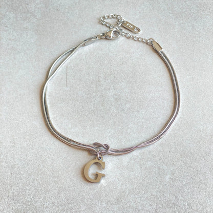 Elegant letter charm bracelets for women in gold and silver tones, featuring a delicate snake chain design and personalised letter charms.