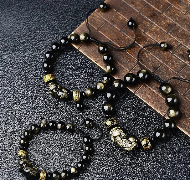 Handmade golden obsidian Pi Xiu bracelet with Chinese zodiac design on wrist.