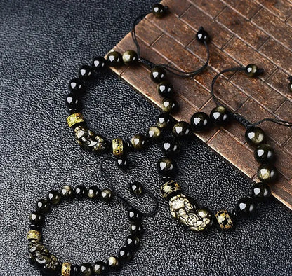 Handmade golden obsidian Pi Xiu bracelet with Chinese zodiac design on wrist.