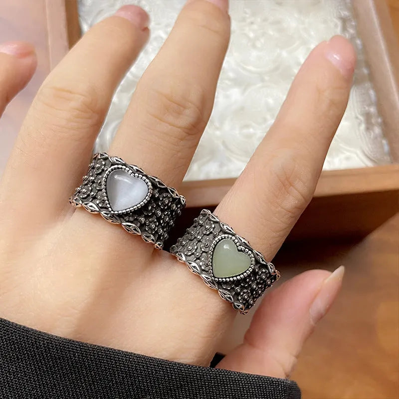 Retro style wide silver heart shape ring with adjustable band on a wooden surface