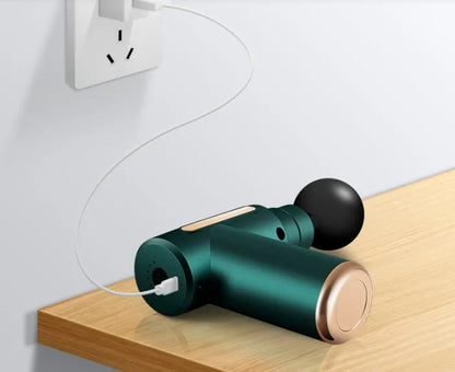 Black electric muscle massage gun with four different coloured massage heads on a grey background.