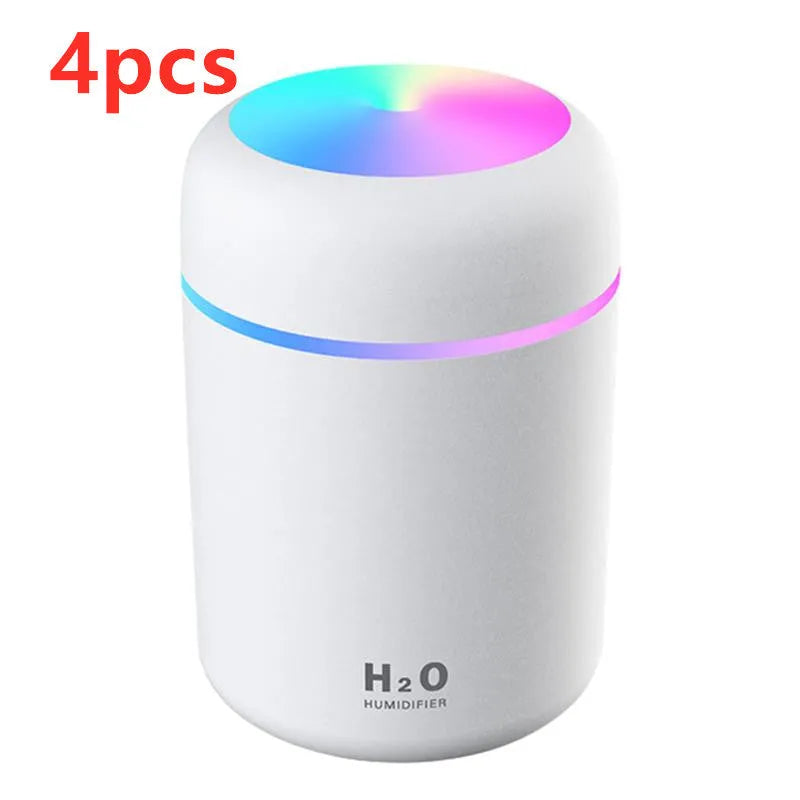 Pink USB desktop humidifier with LED lights and water tank on wooden desk
