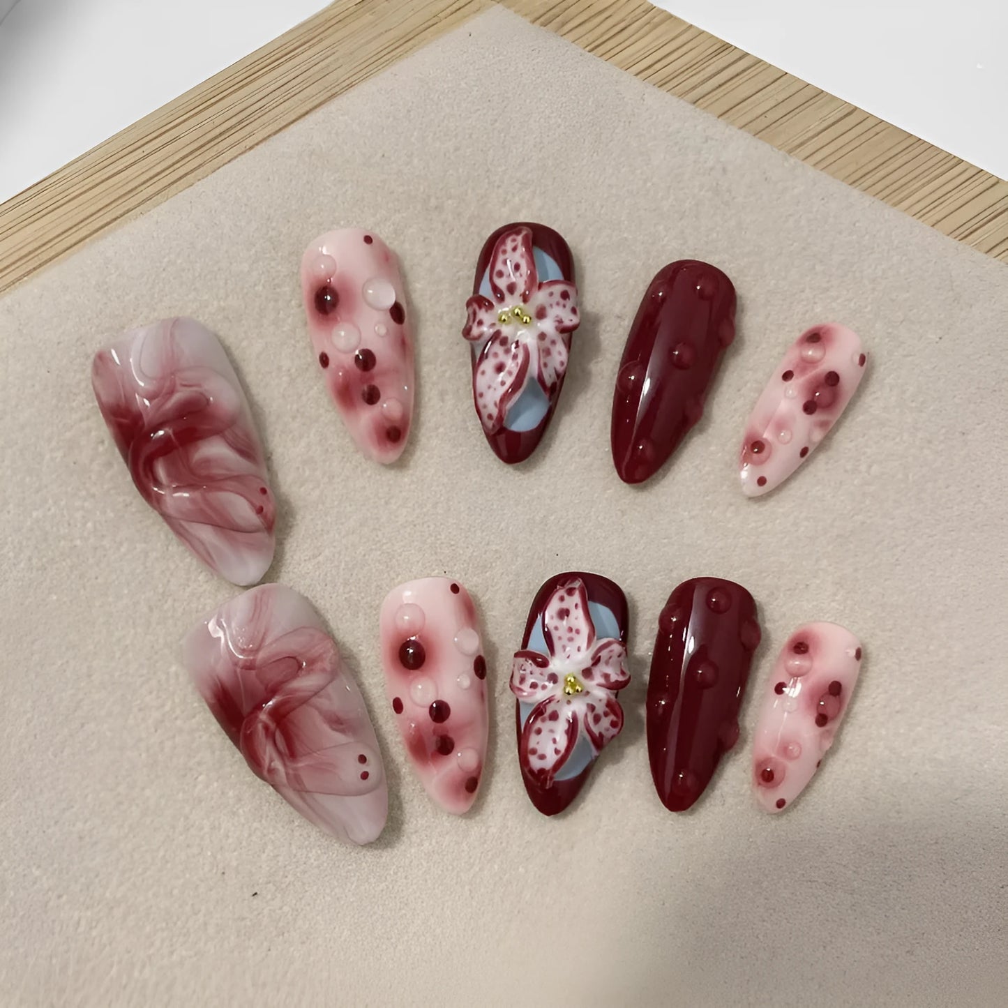 Hand-painted 3D carved nail wraps in Almond colour showing floral and geometric designs for mid-length manicures.