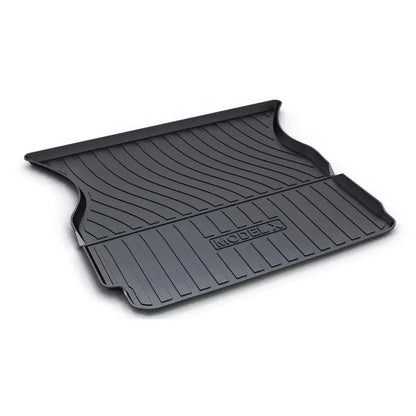 Custom black rubber floor mats fitted in a Tesla Model 3, showing deep grooves and raised edges.