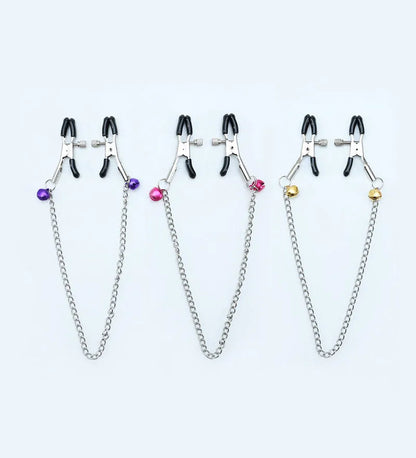 Red and purple nipple clamps with small bells and feather decorations for adult sensory play.