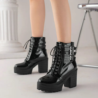 Women's black chunky heel ankle boots with round toe and front lace-up on a wooden floor.