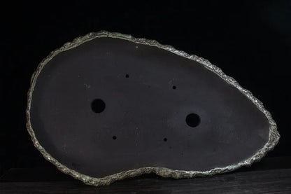 Handmade purple clay flower pot in a creative shape on a floor.