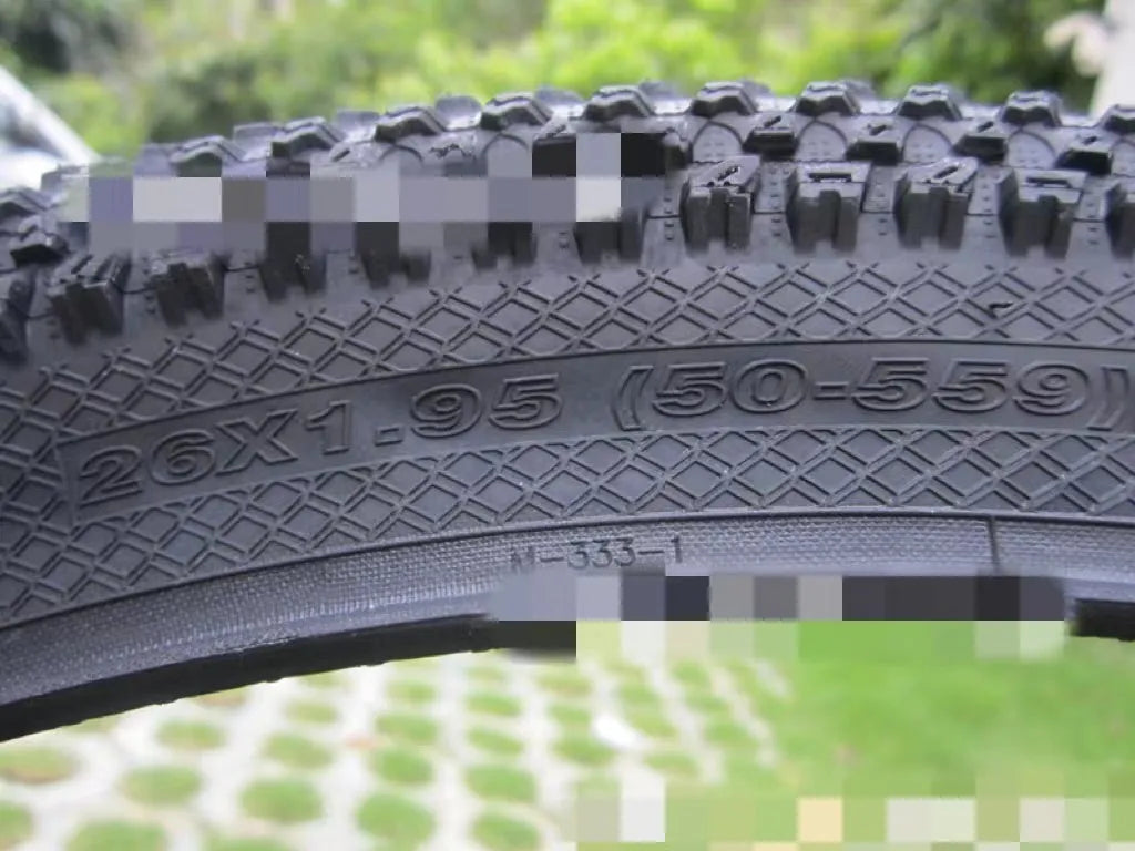 Mountain bike tyre with black tread and sidewall, showing size options like 26x1.95 and 29x2.1 inches for off-road cycling.