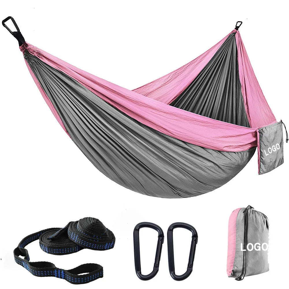 Parachute cloth double camping hammock in chosen colour, with black buckles and round ropes on a tree.