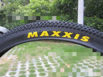 Mountain bike tyre with black tread and sidewall, showing size options like 26x1.95 and 29x2.1 inches for off-road cycling.
