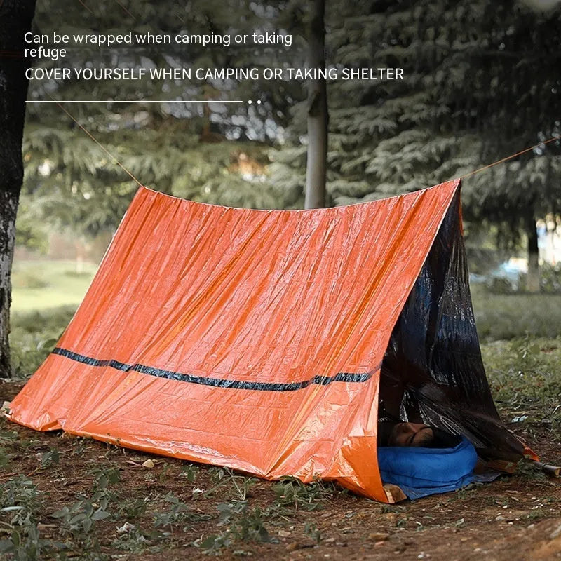 Orange emergency tent with sleeping bag and blanket disaster relief kit on ground