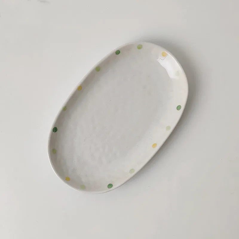 Japanese-style dot pattern porcelain plates and bowls in irregular oval and round shapes on a table.
