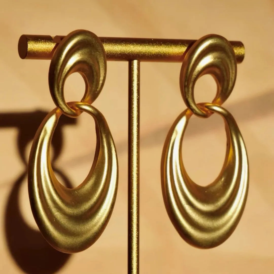 A pair of gold-coloured U-shaped women's earrings with a double circle design on a plain background.