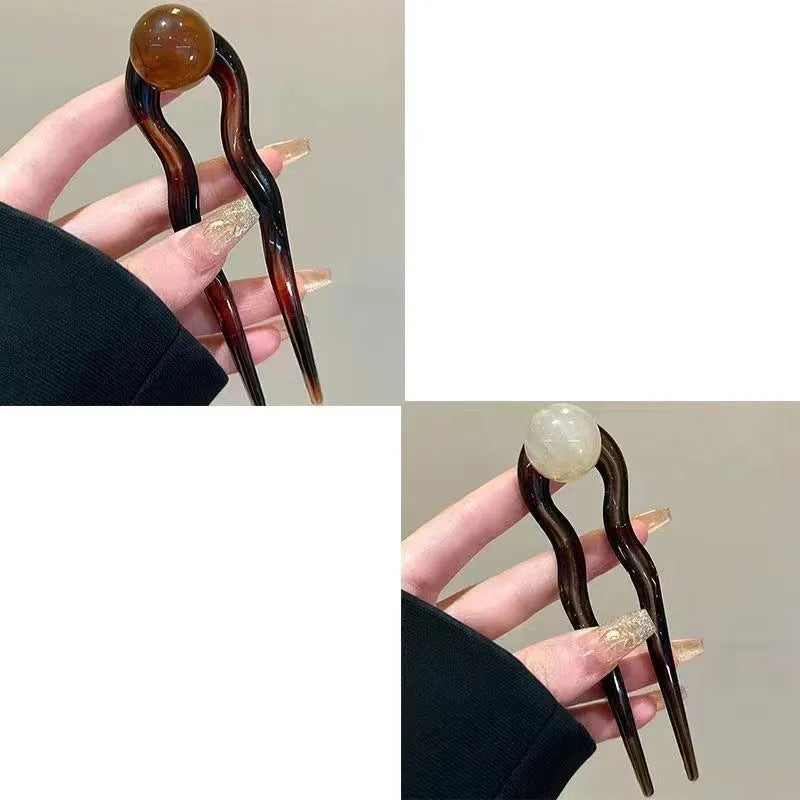 A set of U-shaped acrylic hair barrettes with a simple ball decoration in beige, caramel, and dark grey colours.