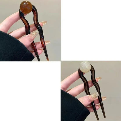A set of U-shaped acrylic hair barrettes with a simple ball decoration in beige, caramel, and dark grey colours.