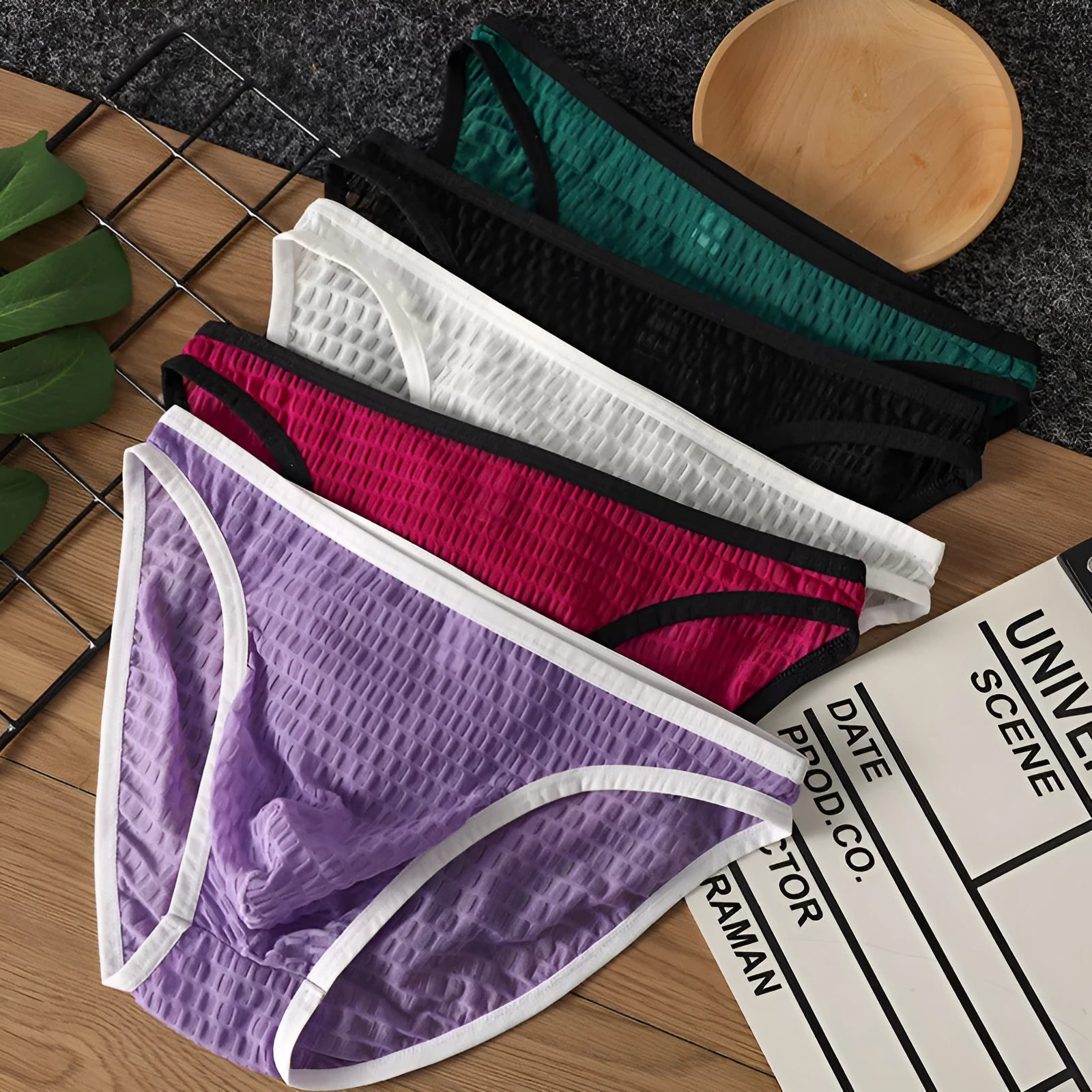 Men's low waist transparent lace underwear in various colours on a size chart background.