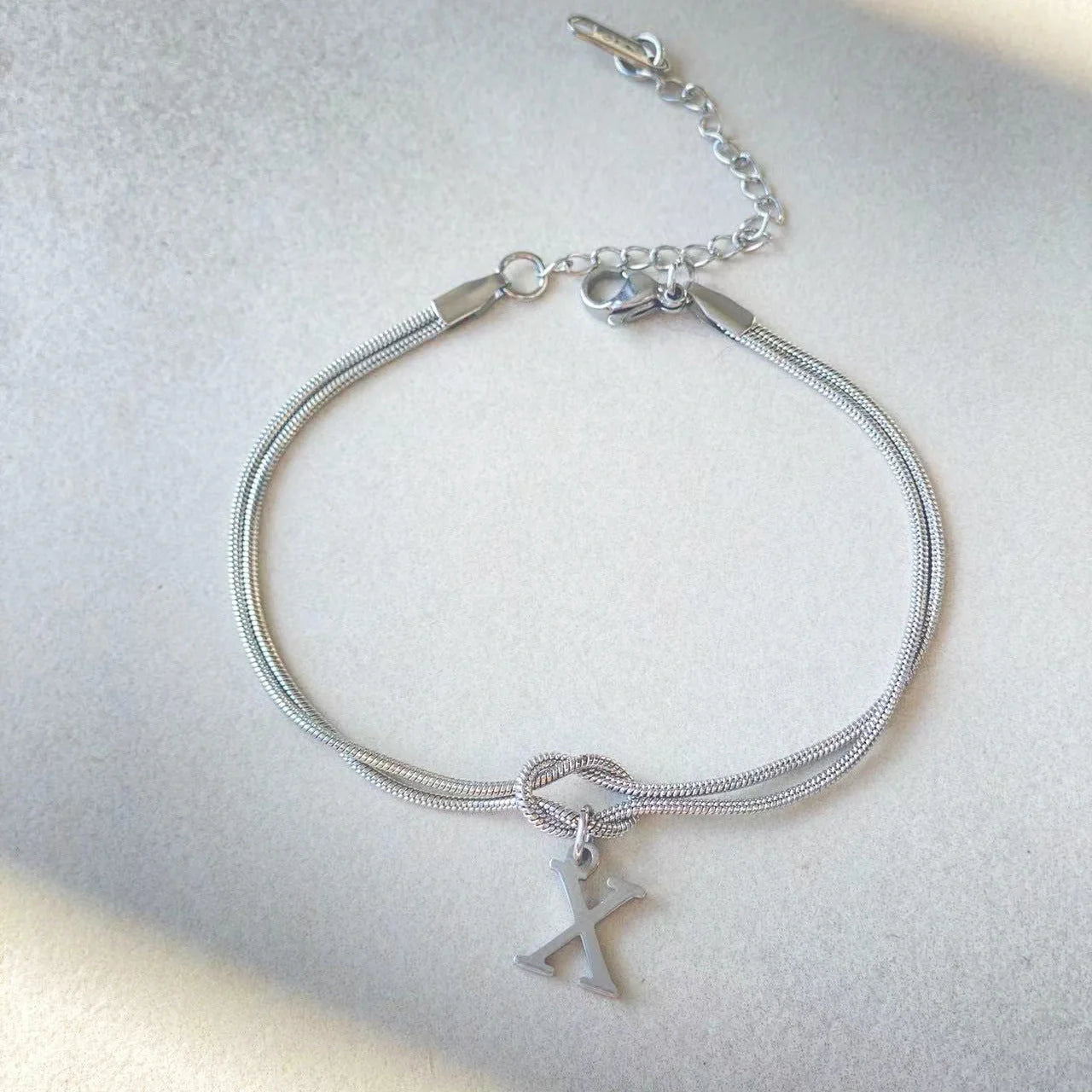 Elegant letter charm bracelets for women in gold and silver tones, featuring a delicate snake chain design and personalised letter charms.