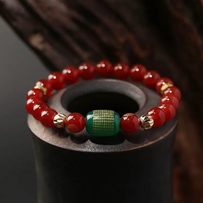 A red agate beaded bracelet with a Guanyin pendant on a white background.