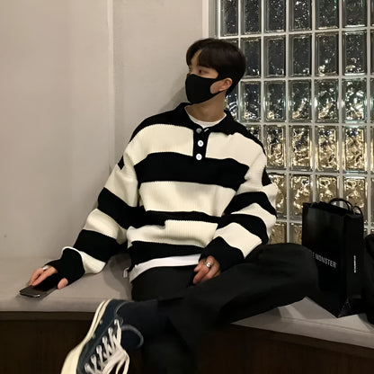 Man wearing a loose grey and black striped long sleeve pullover sweater.