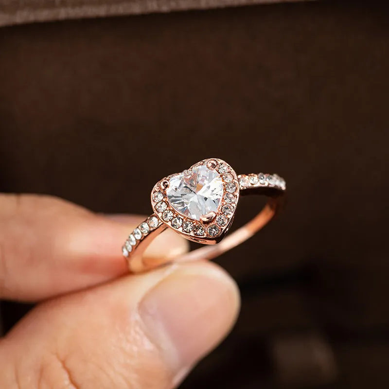 Women's heart-shaped crystal ring in rose gold or silver tone on white copper.