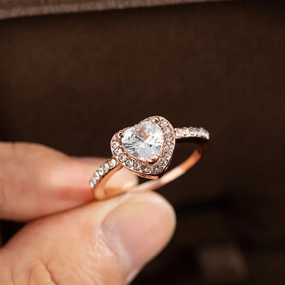 Women's heart-shaped crystal ring in rose gold or silver tone on white copper.