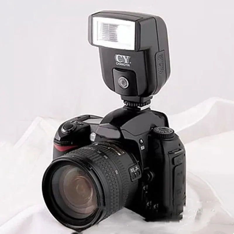 Compact black hot shoe camera flash with its head tilted upwards, showing the flash bulb and hot shoe mount.