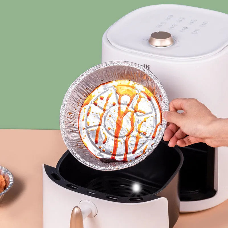 Round disposable aluminium foil liners for air fryers in four different sizes on a kitchen counter.