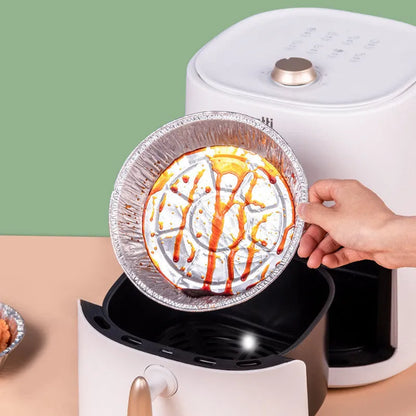 Round disposable aluminium foil liners for air fryers in four different sizes on a kitchen counter.