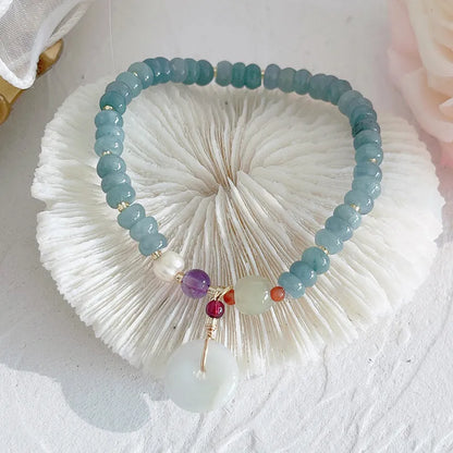 Simple blue jade bracelet with gourd charm, peace buckle, and adjustable cord on woman's wrist