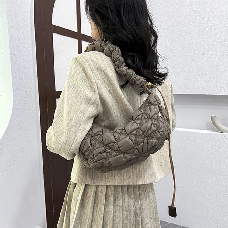 Women's light grey nylon underarm messenger bag with adjustable long strap, shown worn crossbody.
