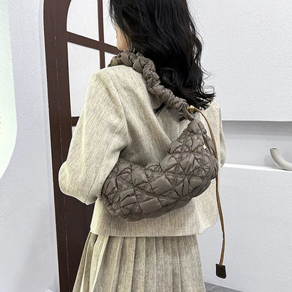 Women's light grey nylon underarm messenger bag with adjustable long strap, shown worn crossbody.