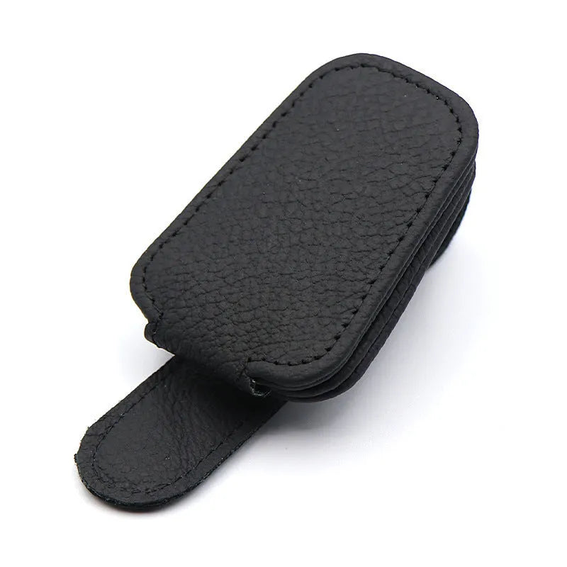 Car sunglasses holder clip with PU leather case attached to a sun visor.