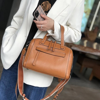 Genuine leather horizontal messenger bag in wine red with shoulder strap and internal zippered compartments.