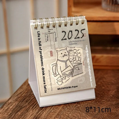 Set of four different themed 2025 mini paper desk calendars on a desk.