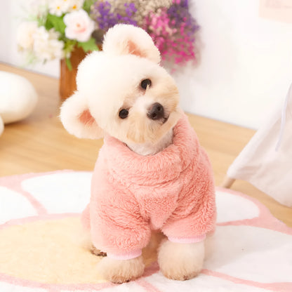 A dog wearing a blue, double-sided plush, four-legged coat with a high collar and a small towing ring visible.