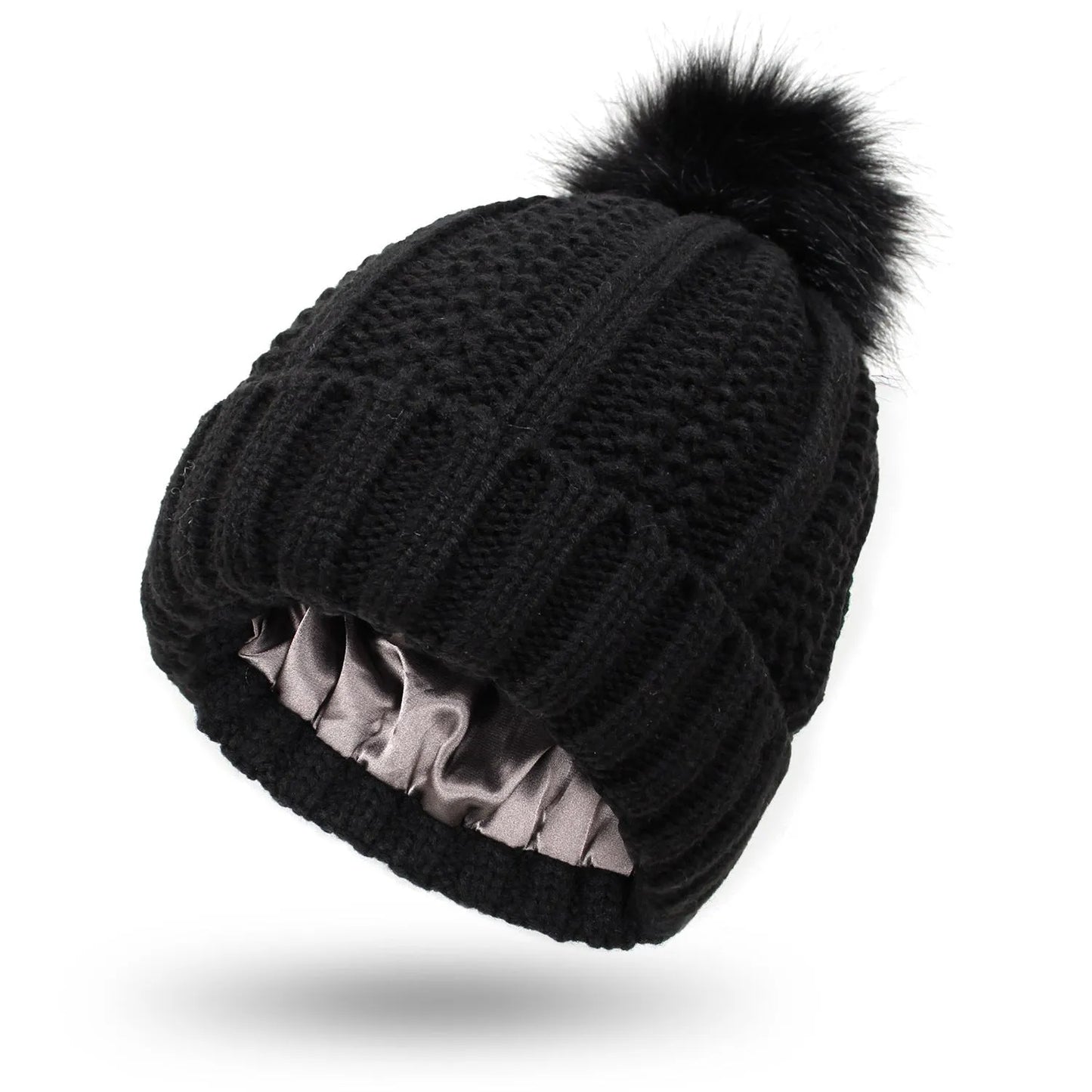 Woman wearing a wine red wool beanie hat with a faux fur pom pom and satin lining.