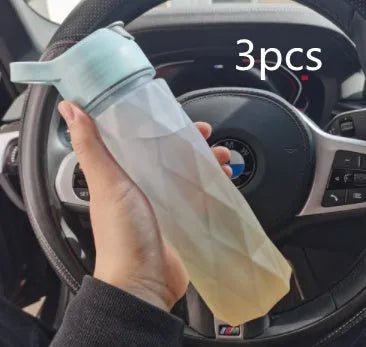 White spray water bottle with black leakproof lid and handle strap on a table
