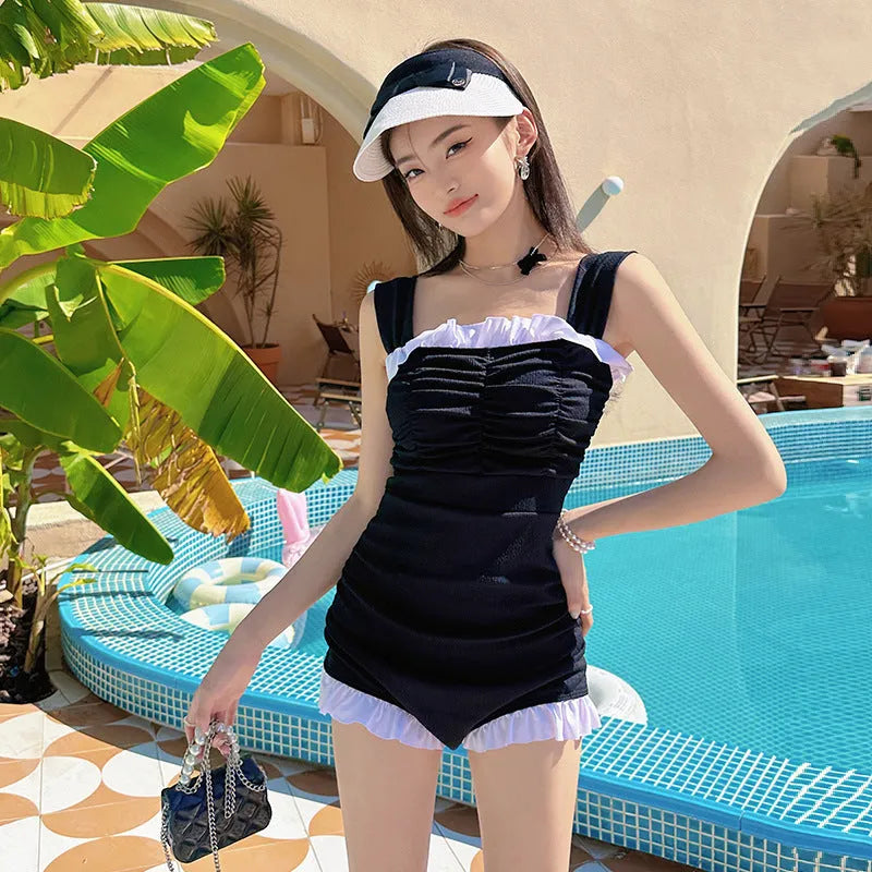 Women's solid colour one-piece swimsuit with suspender straps in a jumpsuit style.